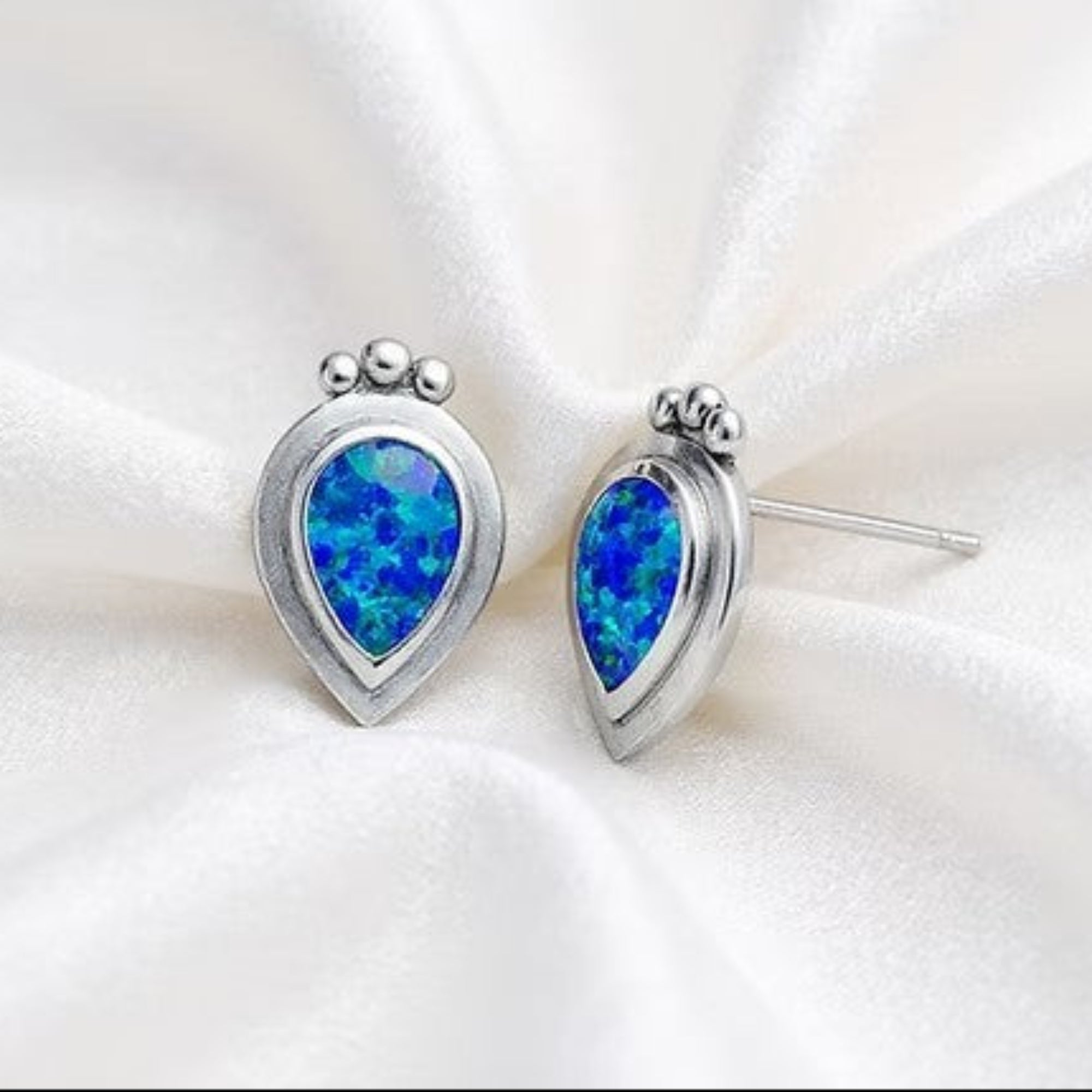 Silver Pear Shaped Studded Earrings on Silk White Background