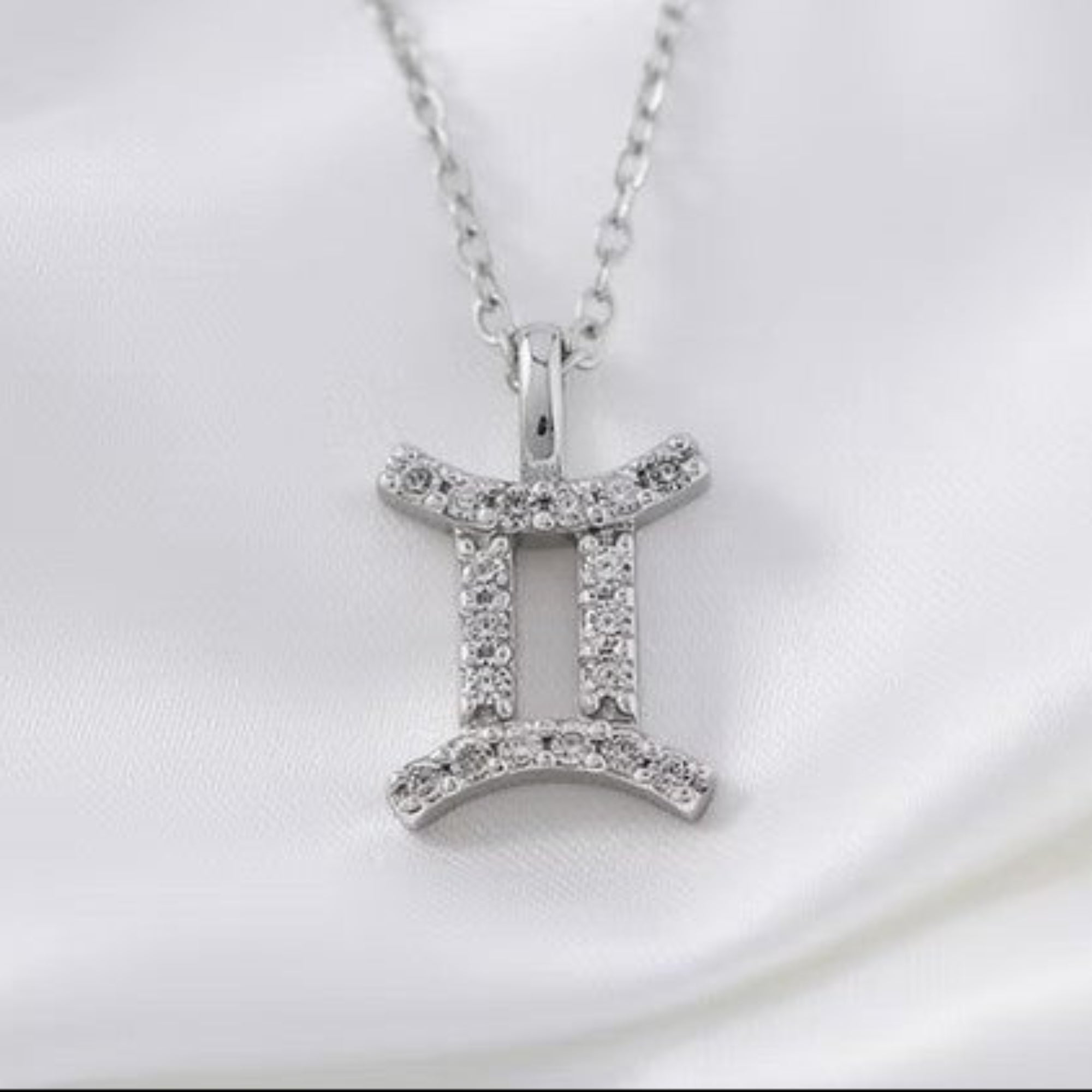 Silver Diamond Zodiac Pendant on White Silk Background