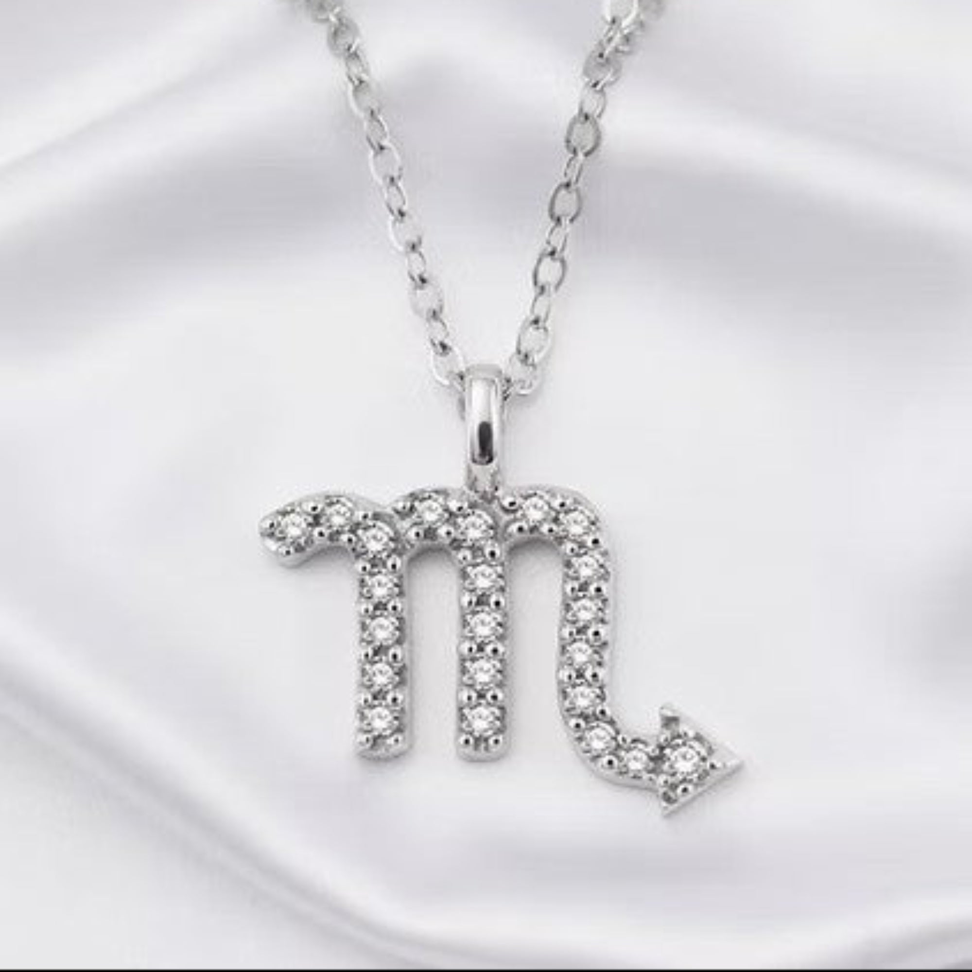 Silver Diamond Zodiac Pendant on White Silk Background